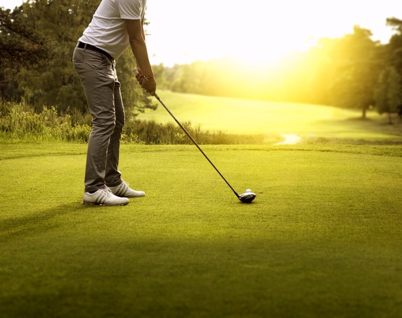 Man Golfing with sunshine and course in front of him